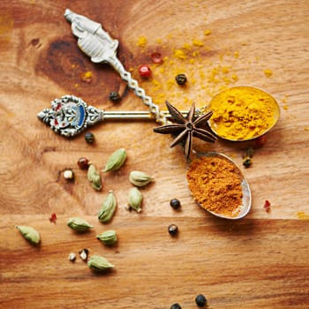 Spoons, spice and selection of seasoning for diet on kitchen table, turmeric and cardamom for meal. Top view, condiments and options for spicy gourmet in Indian culture, art and food preparation.