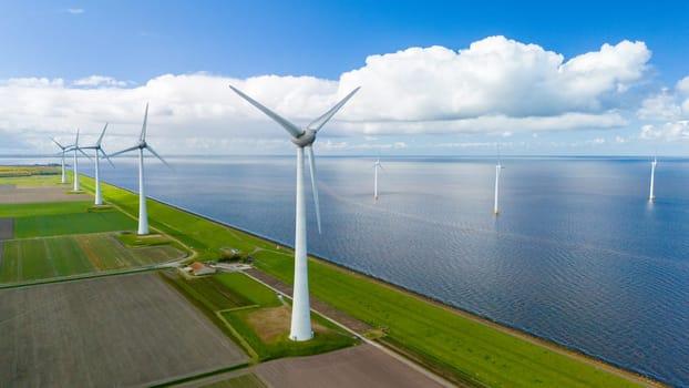 Wind turbines spin gracefully in a wind farm perched near the ocean, harnessing the power of the breeze to generate renewable energy. in the Noordoostpolder Netherlands
