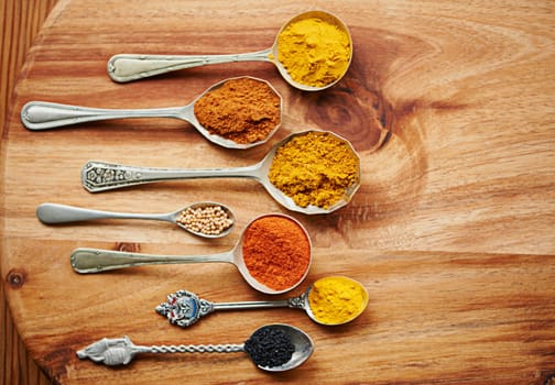 Variety, curry and spices on vintage spoon with natural ingredients to cook dinner. Asian, power and seasonings for hot, spicy and delicious authentic Indian food with flavour on tabletop in kitchen.