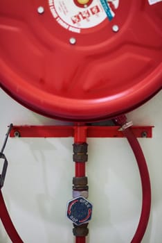 Fire, safety and coiled hose on wall for emergency, danger and rescue with closeup of open mechanics. Water pipe and red extinguisher for building regulation and compliance in case of danger or risk.