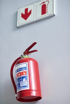 Fire extinguisher, wall and sign for firefighting, action and safety with emergency help and support. Portable dry and chemical powder to stop flame, air and oxygen for building equipment and arrow.