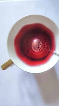 red hibiscus tea in a cup with a strainer, drink. High quality photo