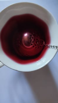 red hibiscus tea in a cup with a strainer, drink. High quality photo