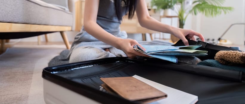 Young woman packing suitcase at home. Travel concept.