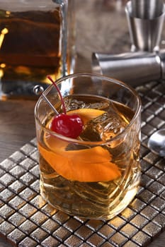 Cocktail Old Fashioned is an old-fashioned sophistication of whiskey and sweet syrup. Served with ice, orange zest and Maraschino cherry. 