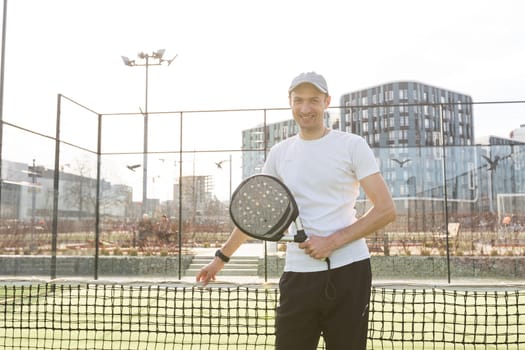 European man holding padel racquet in hand and ready to return ball while playing in court. High quality photo