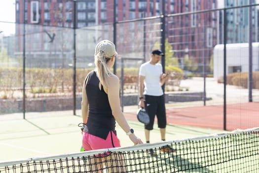 Sportive slim woman with racquet playing padel in court. View from the back. High quality photo