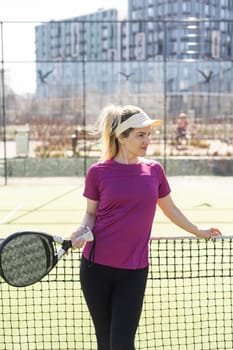 Active young woman trying to beat the ball by Padel racket while playing tennis in the court. High quality photo