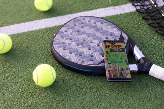 High angle view of mobile phone with tennis equipment on court background. High quality photo