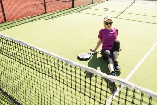 Happy female paddle tennis player during practice on outdoor court looking at camera. Copy space. High quality photo