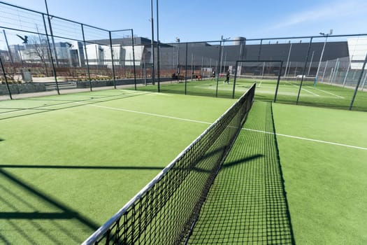 Landscaped areas of a residential development with a tennis court with high Plexiglas and metal fences. High quality photo