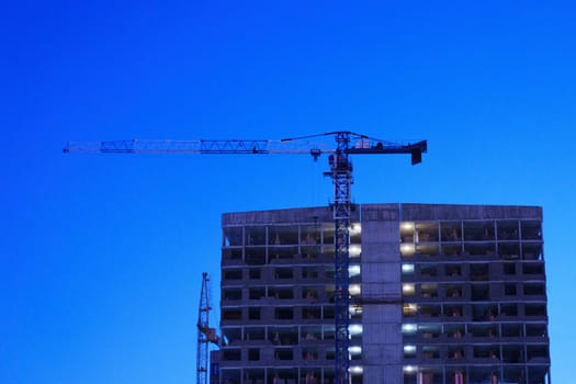 Urban Skyline, construction cranes at night, construction site. Selective focus