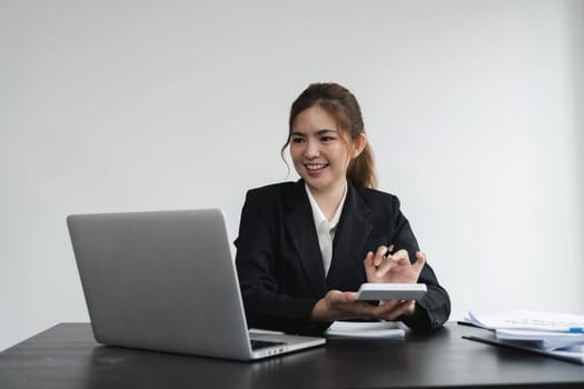 Business woman using calculator and laptop for do math finance on wooden desk in office and business working background, tax, accounting, statistics and analytic research concept.