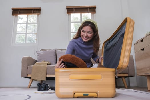 Asian woman packs her suitcase, packing her belongings, clothes and travel documents before going on vacation. Lifestyle concept.