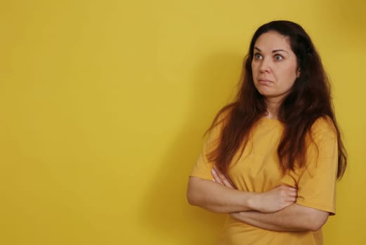 A pretty brunette woman in a yellow T-shirt in a state of bewilderment and consternation.