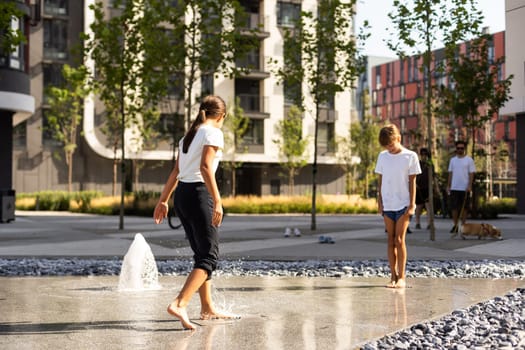 Little girls cool off in a fountain on a hot summer day. High quality photo