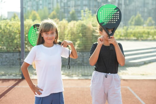 Young girls, athletes shaking hands before game session. Playing tennis on warm sunny day at open air tennis court. Concept of sport, hobby, active lifestyle, health, endurance and strength, ad. High quality photo