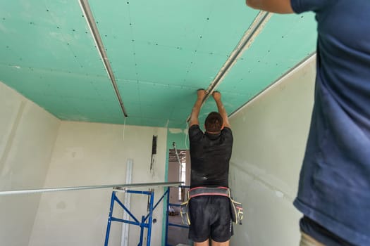 Two workers are mounted ceiling in the new flat. High quality photo