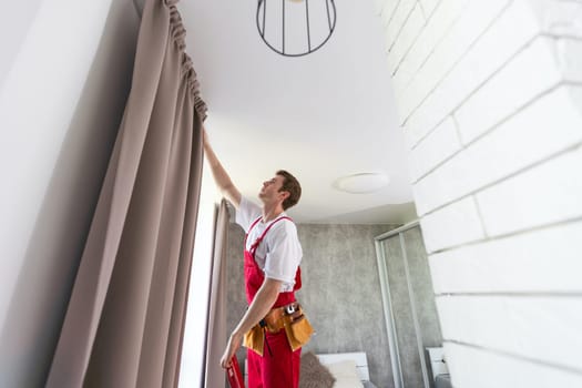 worker installing window curtain rod on the wall.