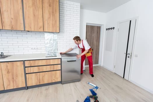 Concept maintenance service of home appliances. Worker cleans filter in the dishwasher. Male repairman checking food residue filters.