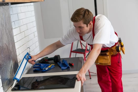 craftsman installs hob in kitchen. Household Appliance Installation Services Concept