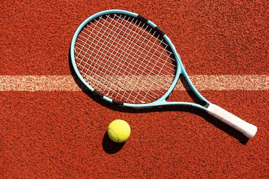 Racket with a tennis ball on a red clay court. High quality photo