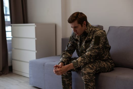 Nervous male military suffering depression, sitting alone at home, PTSD concept