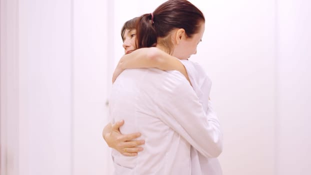 Female doctor crying receives a hug and support from her coworker in the clinic