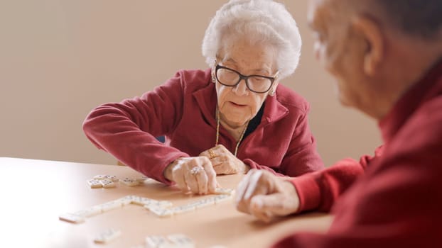 Senior people playing dominoes patiently in a nursing home