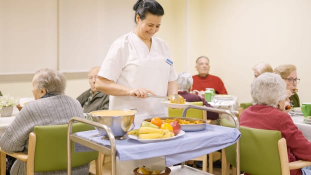 Friendly cook serving food to seniors in a nursing home