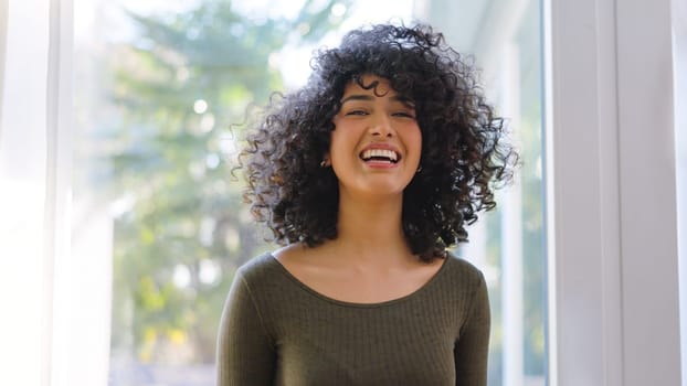 Beauty african woman with curly hair laughing at camera at home