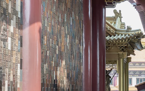 Bangkok, Thailand - Apr 11, 2024 - Golden gable roof and slab of colored tiles on temple wall at Fo Guang Shan Thaihua Temple. Architecture exterior of Taiwanese temple style, Space for text, Selective focus.