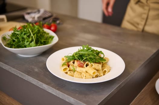 Fresh Italian pasta with green arugula leaves on kitchen table