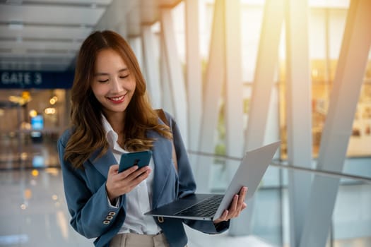 Efficient woman multitasking with laptop and cell phone, staying organized and productive during travel.