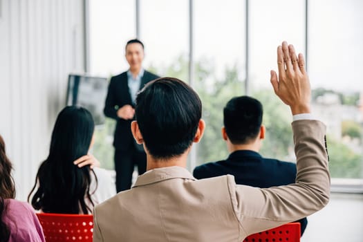 At a conference, hands are raised for questions, underlining the active participation of the audience. A diverse group collaborates in a workshop or seminar, emphasizing teamwork and discussion.