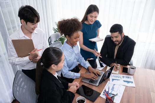 Multiracial analyst team use BI dashboard data to analyze financial report on meeting table. Group of diverse business people utilize data analysis by FIntech for success business marketing. Concord