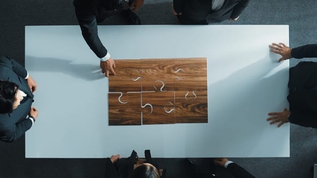 Top view of business people putting jigsaw together at meeting room. Professional marketing team standing at table while gathering puzzle piece. Show unity, cooperation and team working. Directorate.