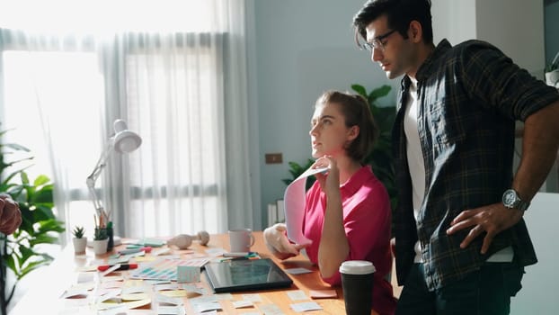 Business people working together while planning marketing strategy at meeting table. Caucasian marketing team looking at whiteboard while thinking about financial plan at meeting room. Symposium.