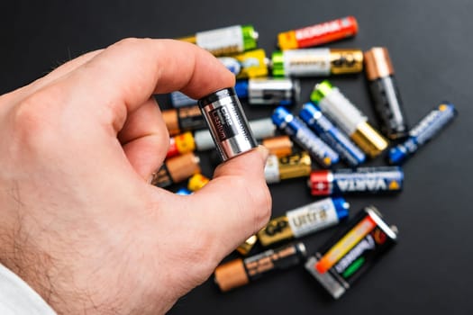 BERLIN , GERMANY - APRIL 14 2024: Small used CR2 alkaline batteries of AA size in mans hand and on the black table.