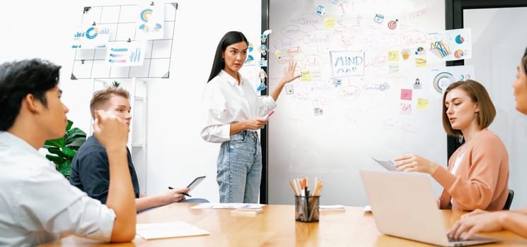 Young beautiful leader presents marketing strategy while expert investor and project manager lecturing to analyze business performance at start up business meeting. Multiethnic group. Immaculate.