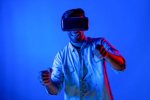 Smart man wear virtual goggle while move driving car hand gesture. Caucasian teenager using futuristic digital technology to enter virtual world while standing at colorful neon background. Deviation.