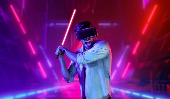 Gamer holding laser sword and playing action game while wearing VR glasses. Caucasian man using visual reality headset while standing and surrounding by neon castle. Innovation technology. Deviation.