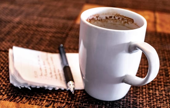 Cup of coffee with notepad and ballpoint pen on table in Playa del Carmen Quintana Roo Mexico.