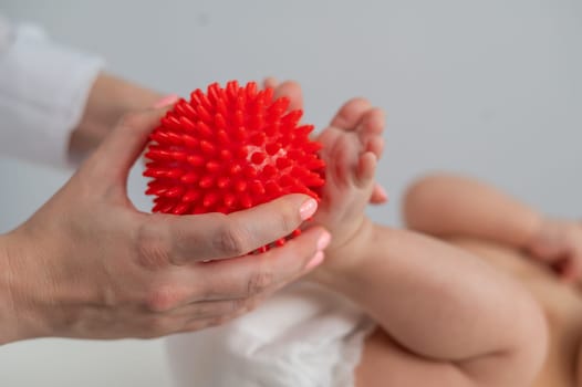 A doctor massages a baby's foot using a spiked ball