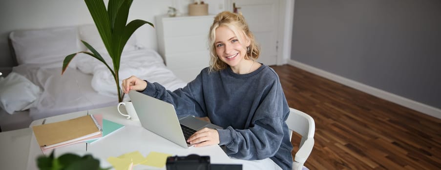 Portrait of young beautiful woman, social media influencer, recording video tutorial, lifestyle vlog, creating content in her room using digital camera.