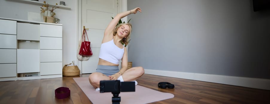 Young athletic woman trainer practicing Hatha Yoga, instructor personal training Vasisthasana, balancing pose, workout at home. Concept of healthy lifestyle and wellbeing.