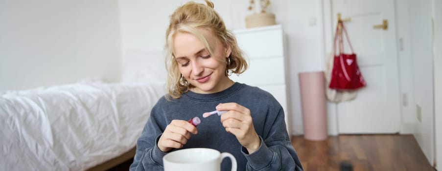 Portrait of young blond girl, puts on lip gloss while getting ready for party. Lifestyle blogger, woman content creator recording video of her with makeup.