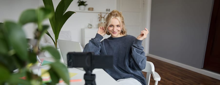 Portrait of young woman, lifestyle blogger, recording vlog video about her life and daily routine, sitting in front of laptop, talking to followers, sitting in her room.