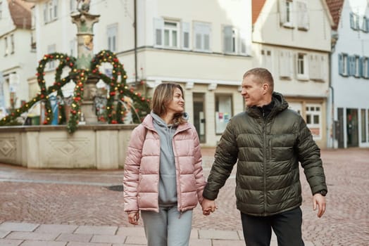 Loving couple of tourists walking around old town. Man woman couple walking europe old town Germany. Couple of lovers leisurely stroll in the cool autumn morning on the streets of a BIETIGHEIM-BISSINGEN (Germany). The guy holds his wife. Vacation, autumn, holiday. Couple Walking in Europe's Old Town