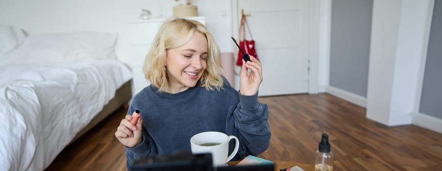 Young charismatic beauty blogger, teenage girl records video of her applying mascara, reviewing makeup products for her lifestyle vlog, vlogging for social media account.